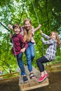 Smiling kids having fun at playground. Children playing outdoors in summer. Teenagers riding on a swing outside