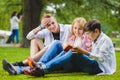 Smiling kids having fun and reading book at grass. Children playing outdoors in summer. teenagers communicate outdoor