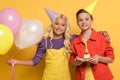 Kids with party caps holding balloons and plate with birthday cake on yellow background Royalty Free Stock Photo