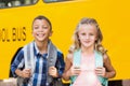 Smiling kids standing in front of school bus Royalty Free Stock Photo