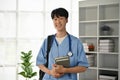 A smiling and kind young Asian male doctor or medical student in scrubs stands in the office Royalty Free Stock Photo