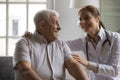 Smiling kind young nurse cuddling shoulders of elderly mature patient. Royalty Free Stock Photo