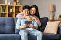 Smiling korean couple websurfing on tablet gadget at home Royalty Free Stock Photo