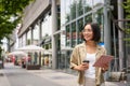 Smiling korean girl walking in city street with tablet, drinking takeaway coffee and looking happy Royalty Free Stock Photo