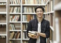 Smiling korean guy holding textbooks at library Royalty Free Stock Photo