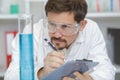 smiling lab technician taking notes while doing sample analysis Royalty Free Stock Photo