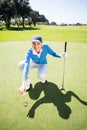 Smiling lady golfer kneeling on the putting green Royalty Free Stock Photo