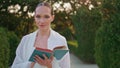 Smiling lady holding book walking at beautiful park alley alone close up. Royalty Free Stock Photo