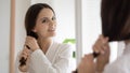 Smiling lady looking at mirror enjoying hair condition after treatment Royalty Free Stock Photo