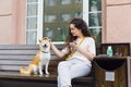 Smiling lady stroking beautiful dog and holding cup of coffee in street cafe Royalty Free Stock Photo