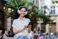Smiling latin american businesswoman enjoying music on headphones while walking in city Royalty Free Stock Photo