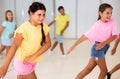 Smiling latin american preteen girl training vigorous dance with tweens