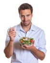 Smiling latin man eating salad