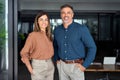 Smiling Latin middle aged business man and woman in office, portrait.