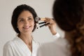 Smiling latin woman hold kit of brushes for professional makeup