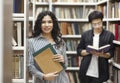 Smiling latin woman holding textbooks at library Royalty Free Stock Photo