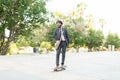 Smiling latin worker riding a skateboard through a green park