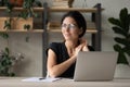 Smiling latina female sit at workplace distracted from laptop screen