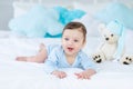 Smiling or laughing baby on the bed to sleep with teddy bear, baby room interior, healthy happy little baby Royalty Free Stock Photo
