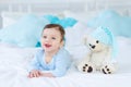 Smiling or laughing baby on the bed to sleep with teddy bear, baby room interior, healthy happy little baby Royalty Free Stock Photo