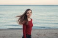 Smiling laughing carefree white Caucasian young beautiful woman with messy long hair on windy day outdoor at sunset on beach