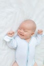 Smiling or laughing in a dream, a newborn baby boy sleeps for seven days in a cot at home on a cotton bed, close-up Royalty Free Stock Photo