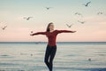 Smiling laughing excited Caucasian young woman in jeans running jumping among seagulls birds Royalty Free Stock Photo