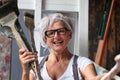 smiling laughing happy older mature woman portrait, proud artist, in her fifties with grey hair and black glasses, with a positive