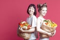 Couple of Smiling Laughing Positive Caucasian Girlfriends With Disposable paper Eco Bags Filled With Grocery And Vegetables Over