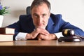 Smiling lawyer in suit leaning on his desk looking at