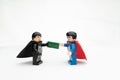 Smiling Lego superhero figures exchanging hundred dollar bills in a cheerful manner