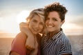 Smiling lesbian couple standing together on a beach at sunset Royalty Free Stock Photo