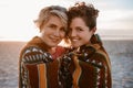 Smiling lesbian couple wrapped in a beach blanket at dusk Royalty Free Stock Photo