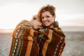 Smiling lesbian couple wrapped in a beach blanket at sunset Royalty Free Stock Photo