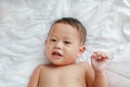 Smiling little Asian baby boy lying on white blanket on bed. Above view Royalty Free Stock Photo