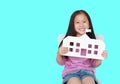 Smiling little Asian child girl holding mock-up paper school isolated on cyan background with copy space. Education and back to Royalty Free Stock Photo