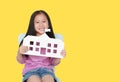 Smiling little Asian child girl holding mock-up paper school isolated on yellow background with copy space. Education and back to Royalty Free Stock Photo