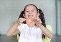 Smiling little Asian child girl holding a piece of sliced tomato. Kid eating healthy food concept. Focus at children face Royalty Free Stock Photo