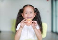 Smiling little Asian child girl holding a piece of sliced tomato. Kid eating healthy food concept. Focus at tomato in children Royalty Free Stock Photo