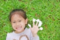 Smiling little Asian child girl lying on green grass lawn with showing empty white stickers on her fingers Royalty Free Stock Photo