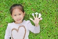 Smiling little Asian child girl lying on green grass lawn with showing white stickers with number one to five on her fingers