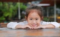 Smiling little Asian child girl lying on the wooden table with looking camera Royalty Free Stock Photo