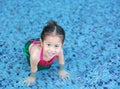 Smiling little Asian child girl in a mermaid suit playing poolside with looking camera Royalty Free Stock Photo