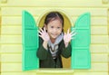 Smiling little Asian child girl playing with window toy playhouse in playground Royalty Free Stock Photo