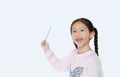 Smiling little Asian child girl standing and pointing up present something isolated over white background. Asian schoolgirl in Royalty Free Stock Photo