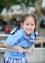 Smiling little Asian girl in school uniform playful hanging at metal stair Royalty Free Stock Photo