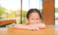 Smiling little Asian kid girl lying on the wood table bar with looking camera Royalty Free Stock Photo