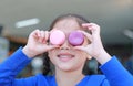 Smiling little Asian kid girl playing and holding Macaroons on her eyes Royalty Free Stock Photo