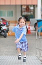 Smiling little Asian kid girl in school uniform running up metal stair Royalty Free Stock Photo