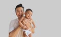 A smiling little baby boy held by his father with grey background and space for text Royalty Free Stock Photo